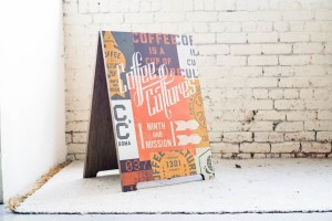 Coffee Cultures signage against an old painted brick wall