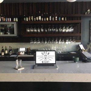 Open Every Night on laptop in a tasteful bar