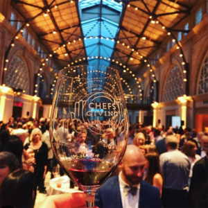 Chefsgiving branded wineglass and event space full of guests