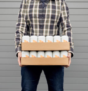 Person holding 2 cases of Elemental Beverage Co. cans