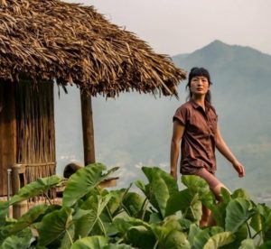 Woman outside a thatched roof structure