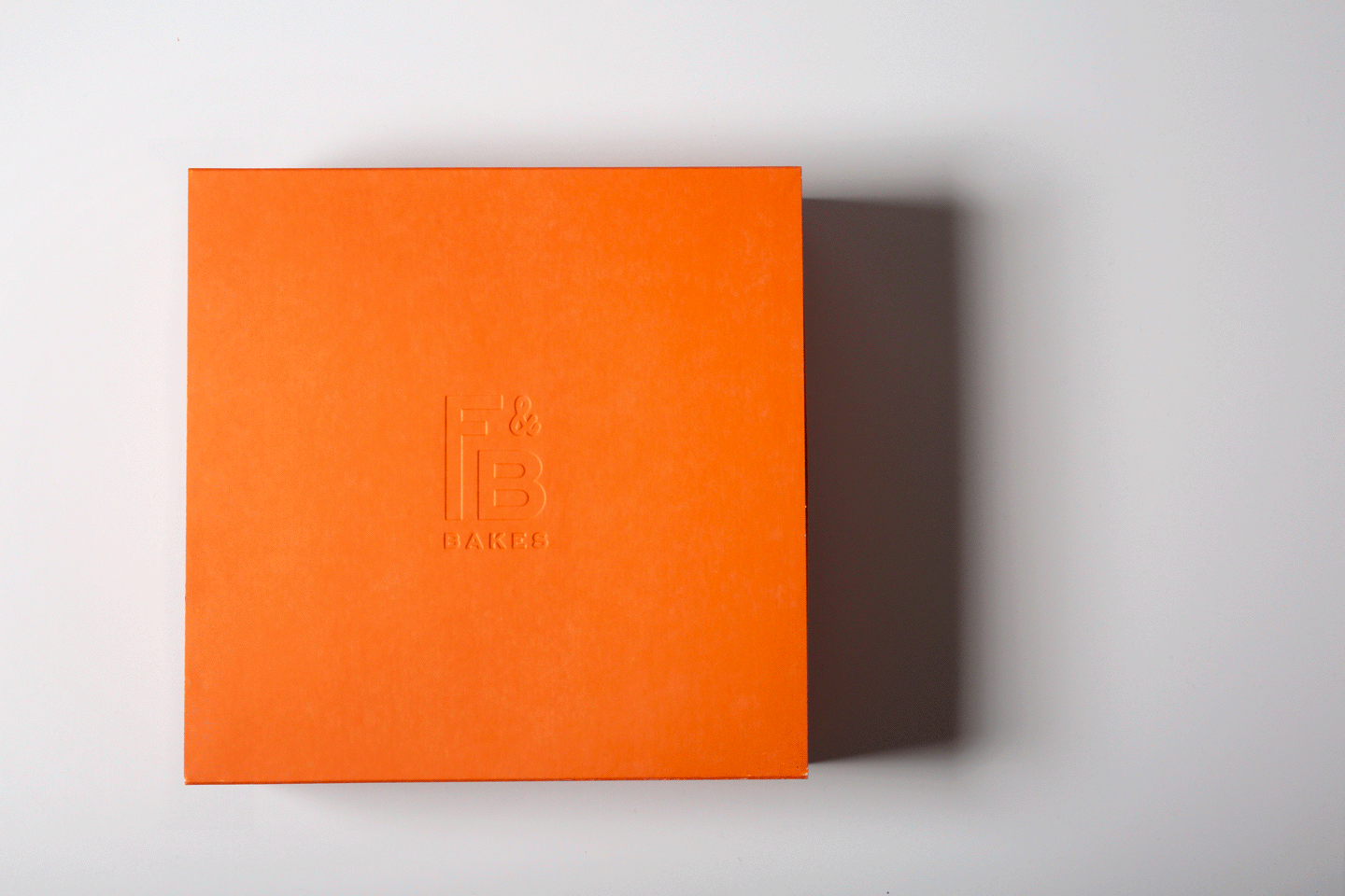 Animation of Flour & Branch debossed orange packaging box sliding open to reveal branded sticker and tissue paper