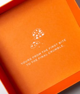 Inside the top of the packaging box, with a brand icon of cookies and the text, "Yours from the first bite to the final crumble"