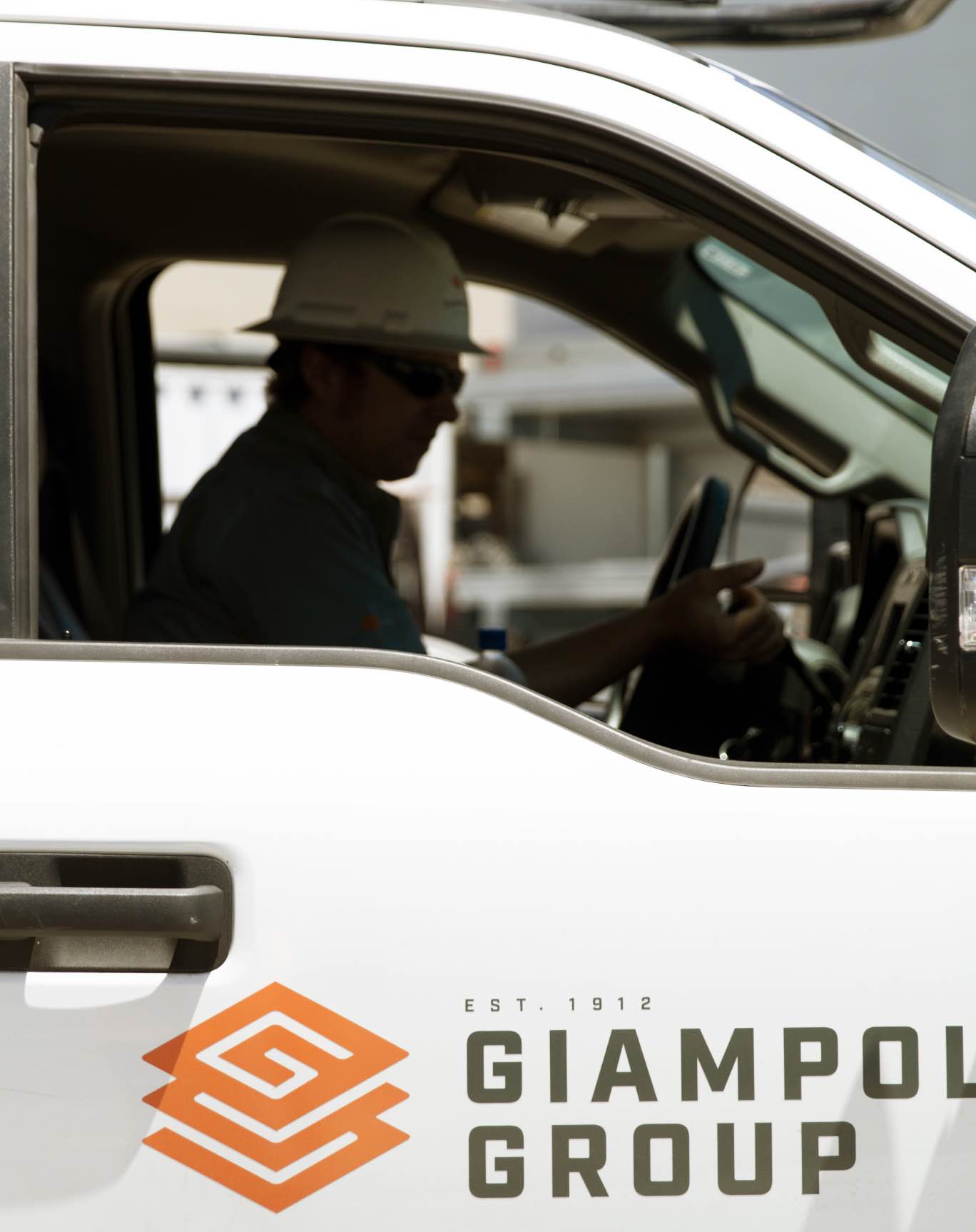 Driver in truck branded with Giampolini Group logo lockup