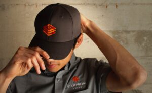 Photo of a man wearing a gray hat and a gray button-down embroidered with the Giampolini Group logo