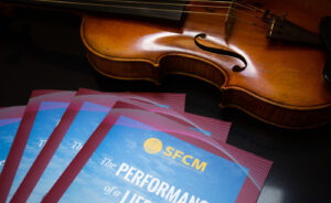 Violin with stack of San Francisco Conservatory of Music lookbooks