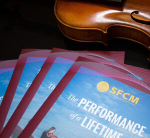 Violin with stack of San Francisco Conservatory lookbooks