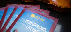 Stack of San Francisco Conservatory of Music lookbooks with violin